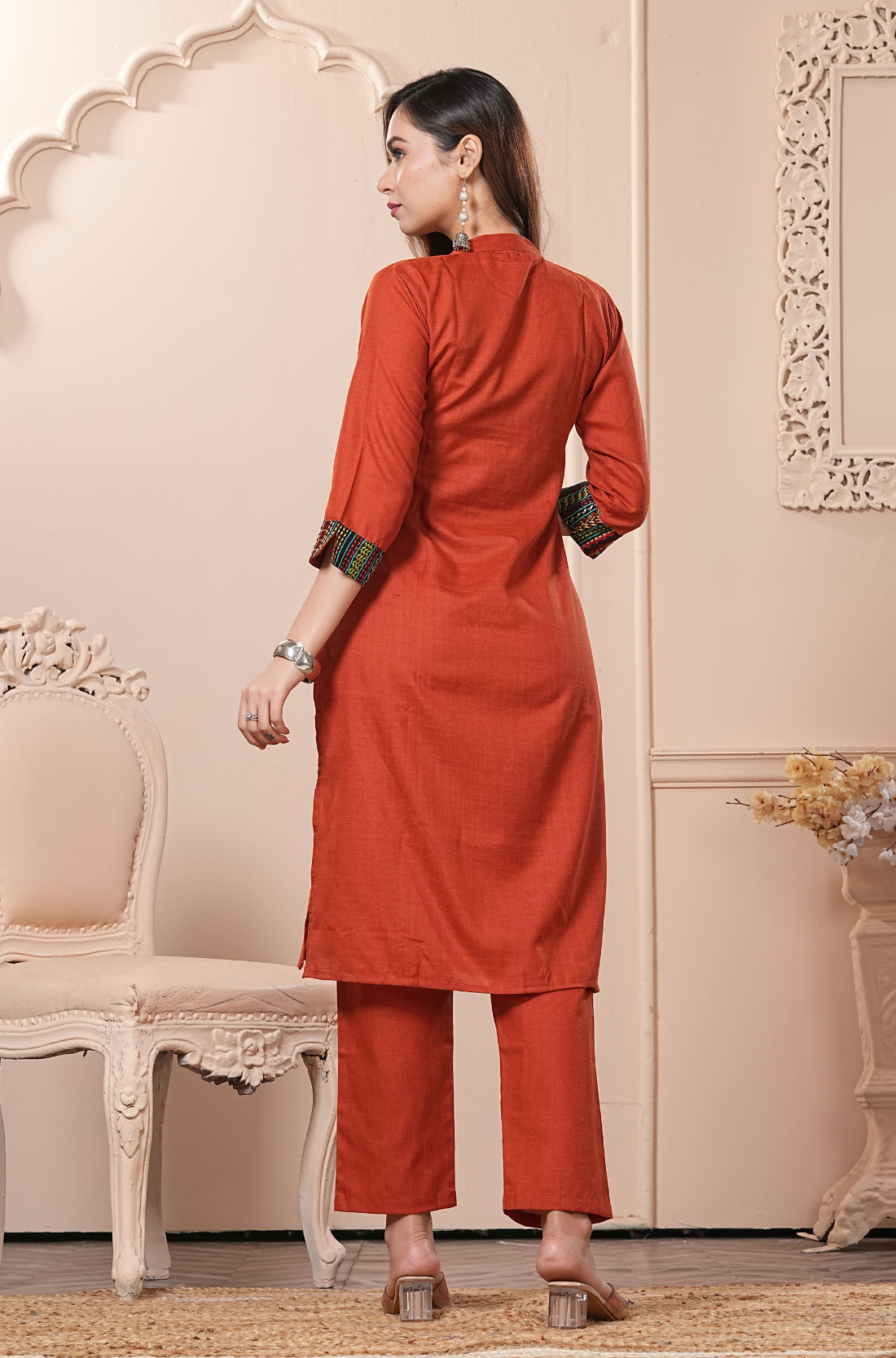 The rear view of a solid rust-toned kurta - showcasing the clean tailored fit of the back - and the matching solid-colored trousers.