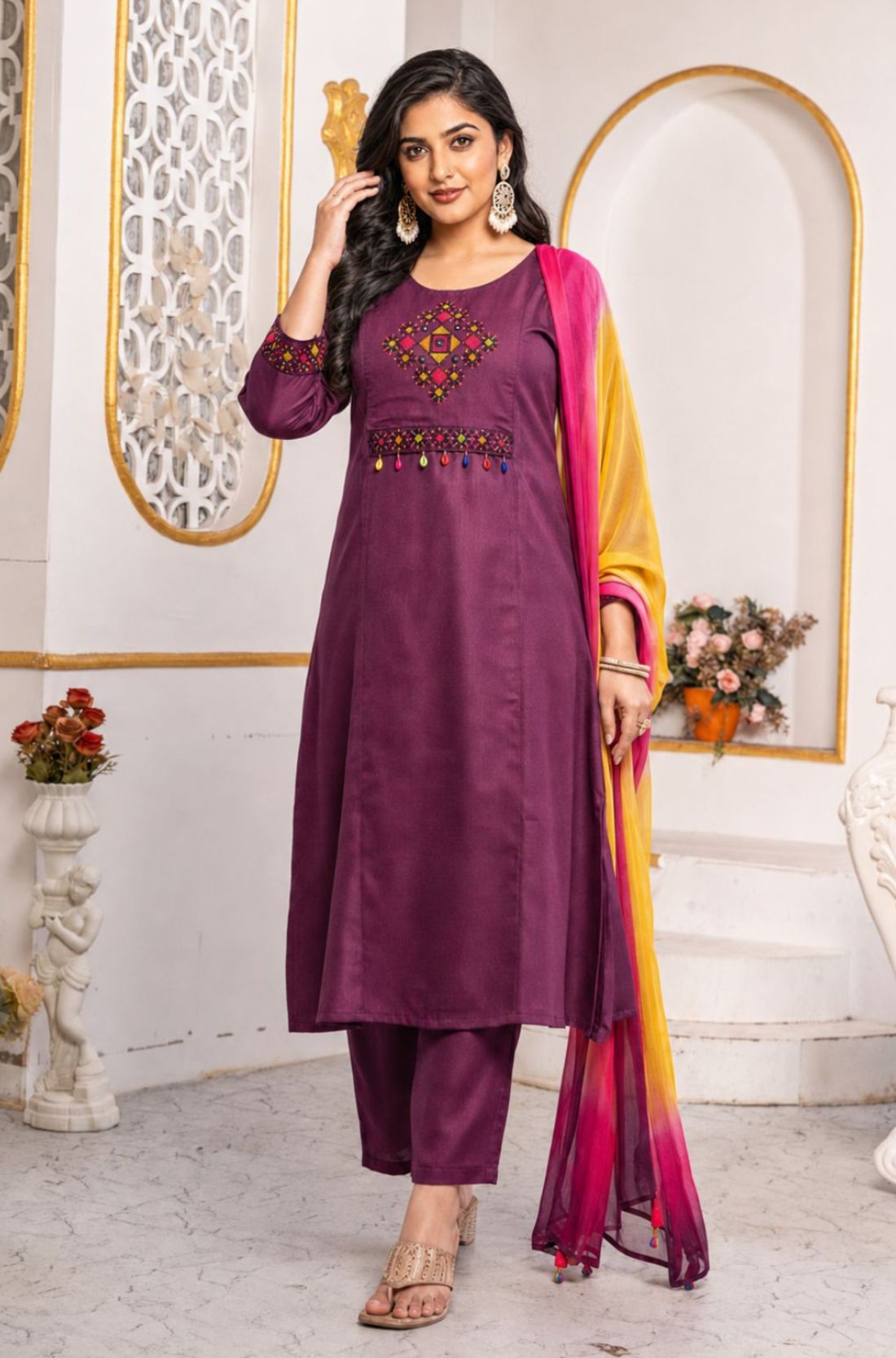 Model wearing a magenta pure cotton kurta pant set featuring multicolour geometric cross-stitch embroidery with mirror detailing, three-quarter sleeves, straight-fit pants and an ombre tie-dye chiffon dupatta.