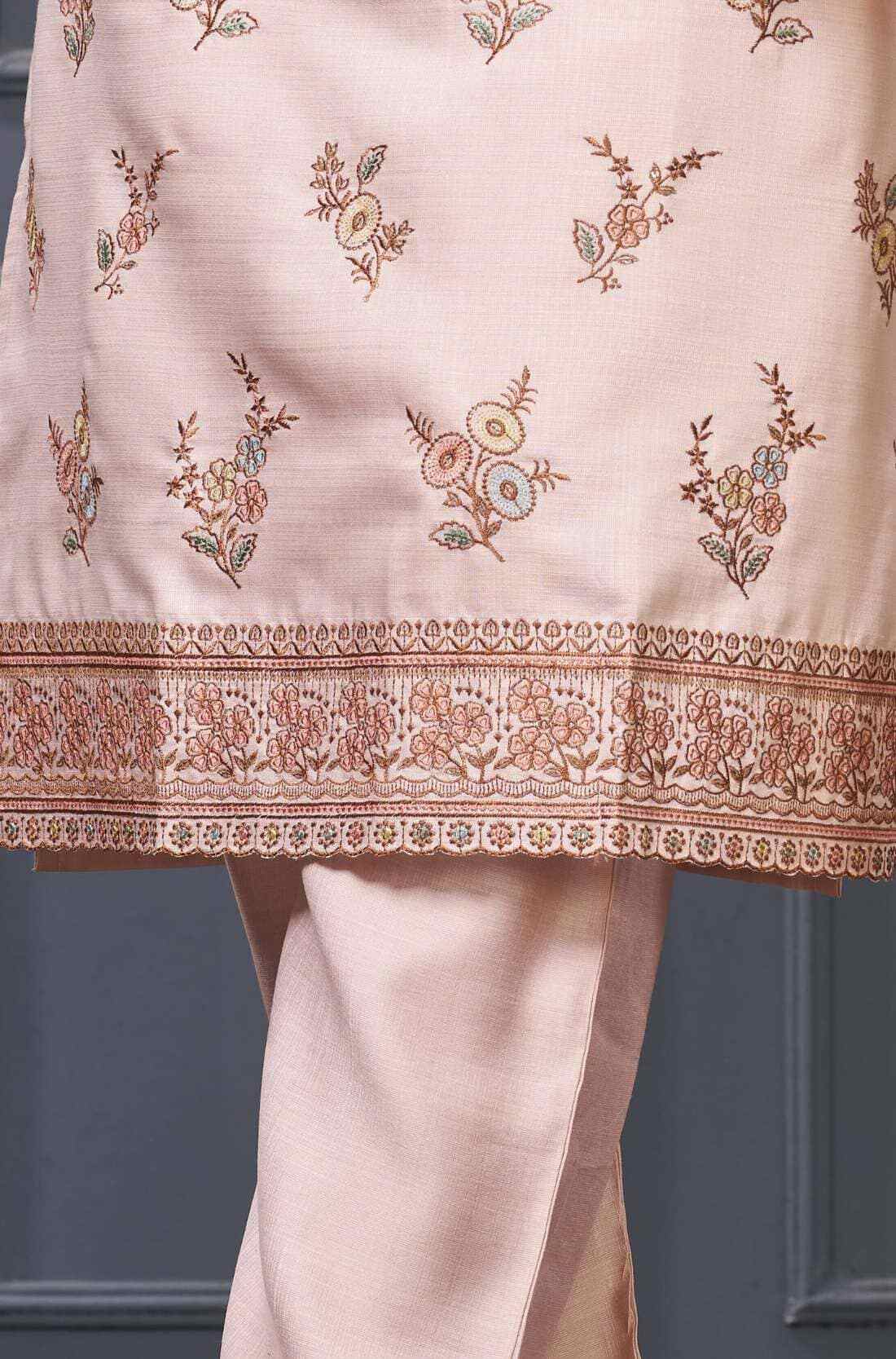 Close-up of pastel kurta set scalloped embroidered border on light pink kurta hem.