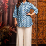 Front view of women's powder blue short kurti crafted from pure cotton with hand block floral print, wooden button placket, 3/4 sleeves, mandarin notch neckline, relaxed fit and side slits paired with white palazzo pants.
