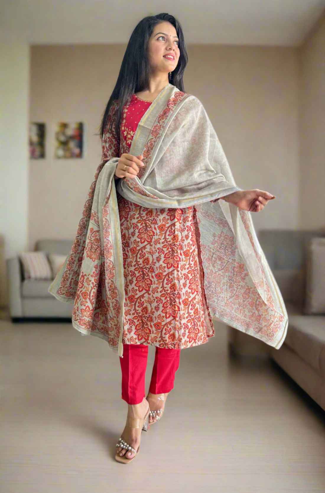 Woman holding dupatta wearing red kurta set.