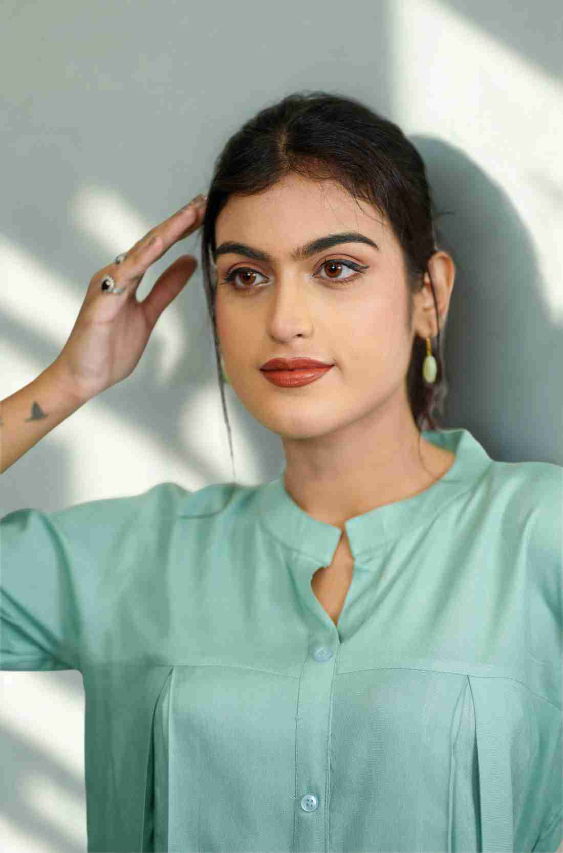 Close-up of the mandarin collar, front button placket, and elegant pleated detailing on a women's sea green rayon formal shirt.