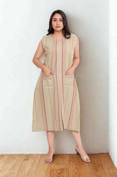 Front view of women's beige cotton striped frock style Kurti featuring a round neckline, sleeveless design, vertical stripes, two front pockets, and a relaxed A-line silhouette for everyday wear.