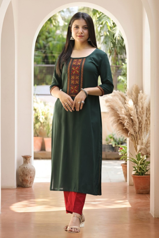 Front view of women's bottle green rayon kurti featuring a round neckline, geometric cross stitch embroidered yoke, contrast embroidered sleeve cuffs and straight fit.