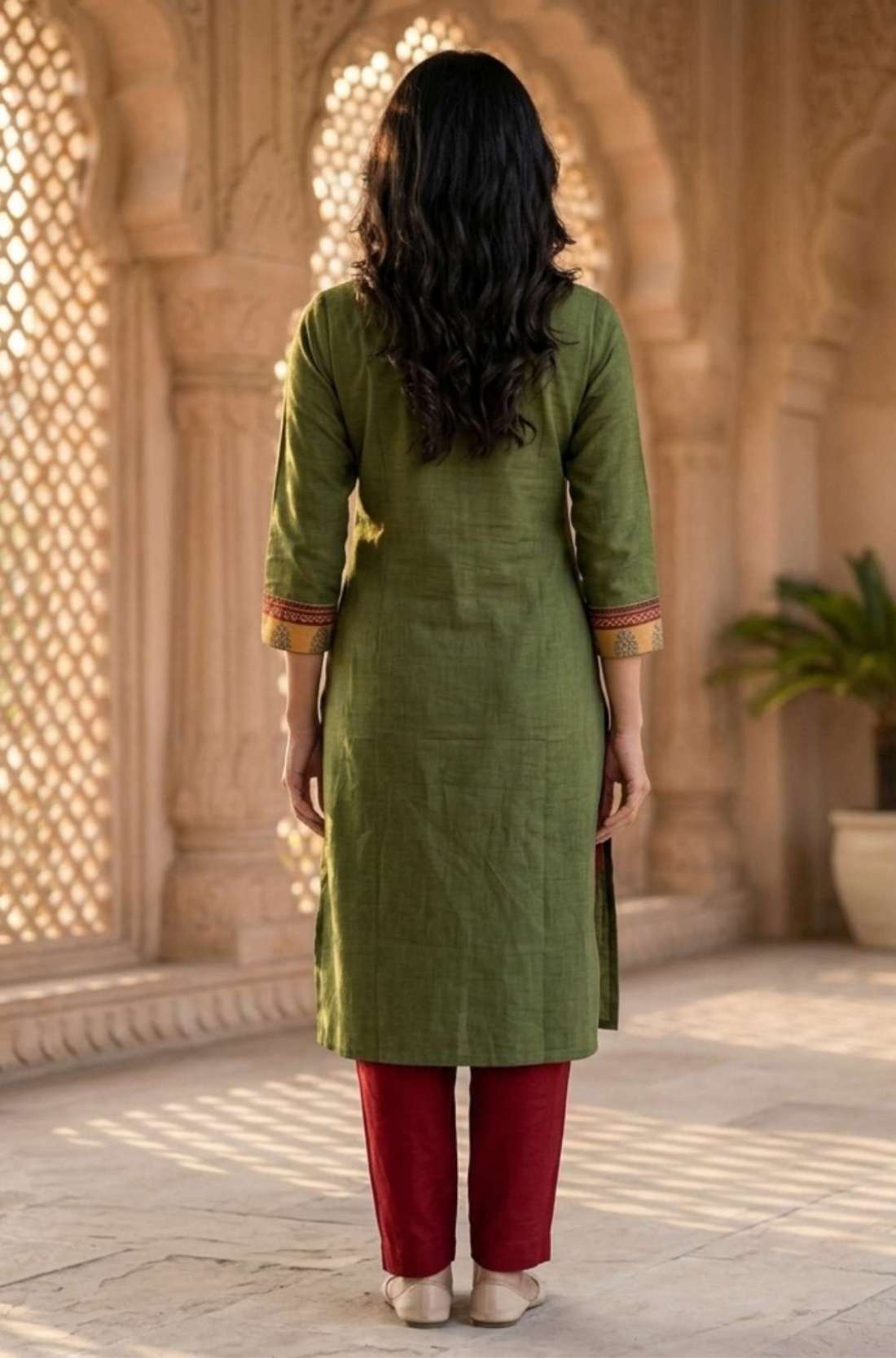 Back view of women's dark green cotton straight-fit kurti with three-quarter sleeves, calf-length design, side slits, and a clean back, paired with maroon pants.