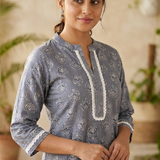 Front view of women's grey cotton straight-fit kurti featuring white block print motifs, a round neckline with lace-accented yoke, three-quarter sleeves with lace cuffs, and breathable cotton fabric.