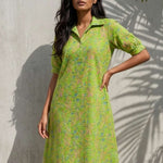 Lifestyle front view of a women's lime green pure cotton frock style dress featuring Jaipur floral print, Kantha stitch detailing, collar neckline, elbow sleeves, and one pocket.