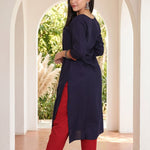 Back view of women's navy blue rayon kurti with a round neckline, 3/4 sleeves, straight silhouette and side slits, paired with red pants.