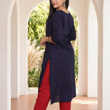 Back view of women's navy blue rayon kurti with a round neckline, 3/4 sleeves, straight silhouette and side slits, paired with red pants.