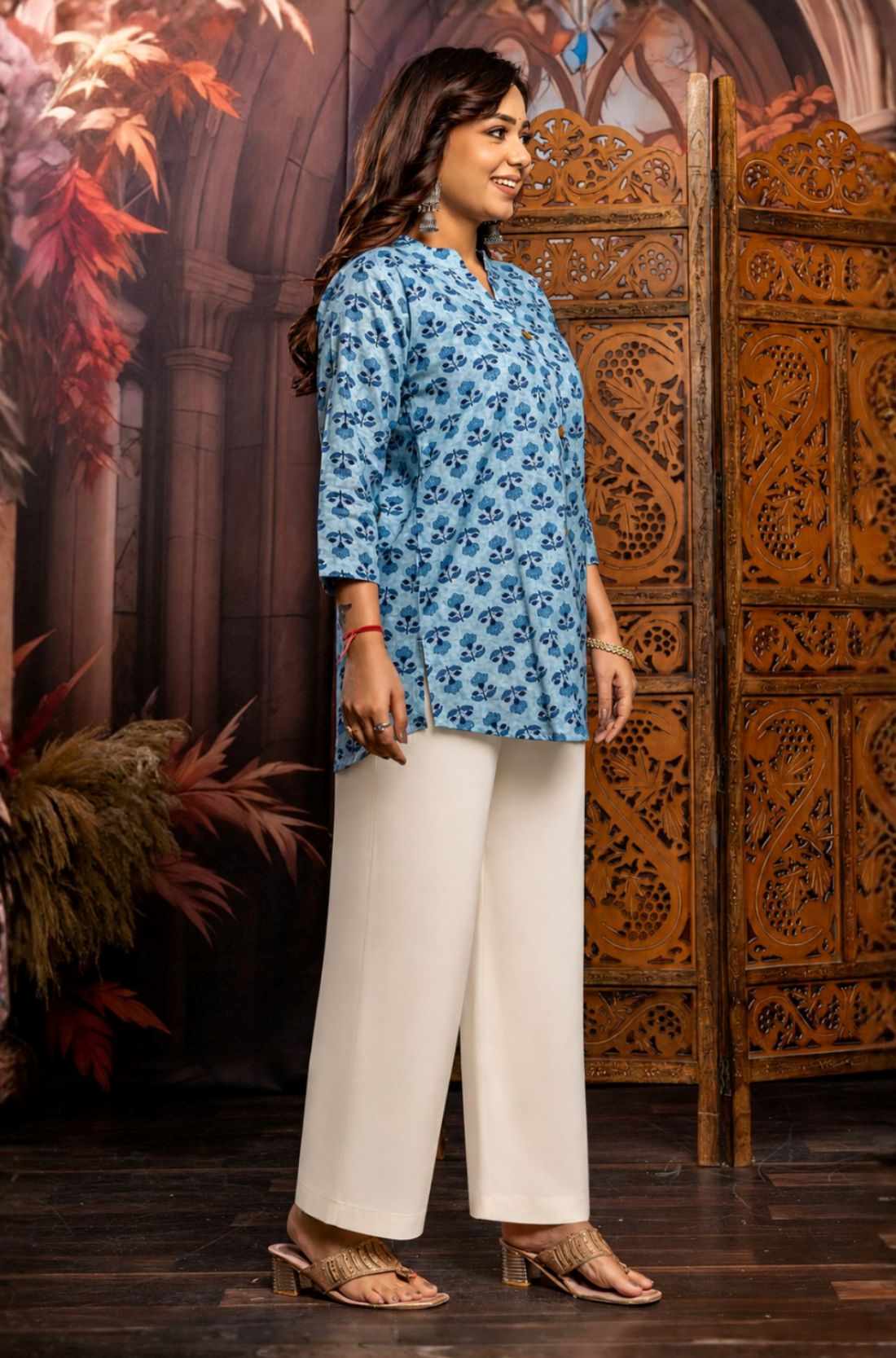 Side profile of powder blue pure cotton short kurti showcasing hand block printed floral motifs, relaxed silhouette, 3/4 sleeves and curved hem for casual ethnic wear.
