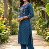 Side view of a women's royal blue anti-crease crepe kurta set featuring a round neckline, hand embroidered yoke, matching trousers, and a gold lycra dupatta with tassels.