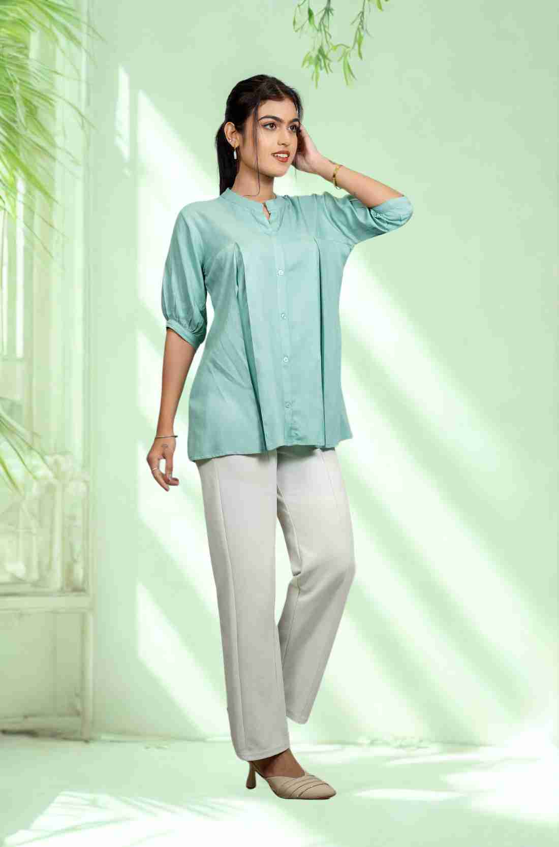 Women's sea green rayon shirt with a mandarin collar, front button placket, soft pleats, and half sleeves styled with white trousers for office and everyday wear.