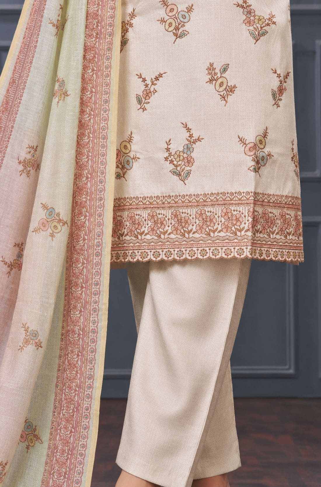 Close-up of floral embroidery and decorative scalloped border on a beige silk blend kurta for women.