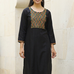 A front-facing studio shot of a woman modeling a black straight-cut kurta with mirror-work detailing.