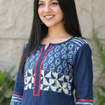 Close-up of a blue kurti with a V-slit neckline, red borders, and white geometric block prints on the yoke.