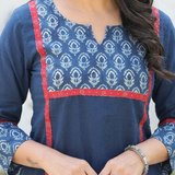 Close-up of a blue cotton kurta featuring a floral printed yoke with striking red border detailing.