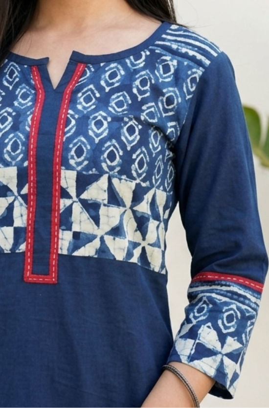Detailed view of the white geometric block print and red stitching details on the yoke and sleeves of a blue kurti.