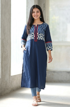 Woman walking confidently wearing a practical blue straight kurti with side pockets, paired with denim jeans and white sandals.