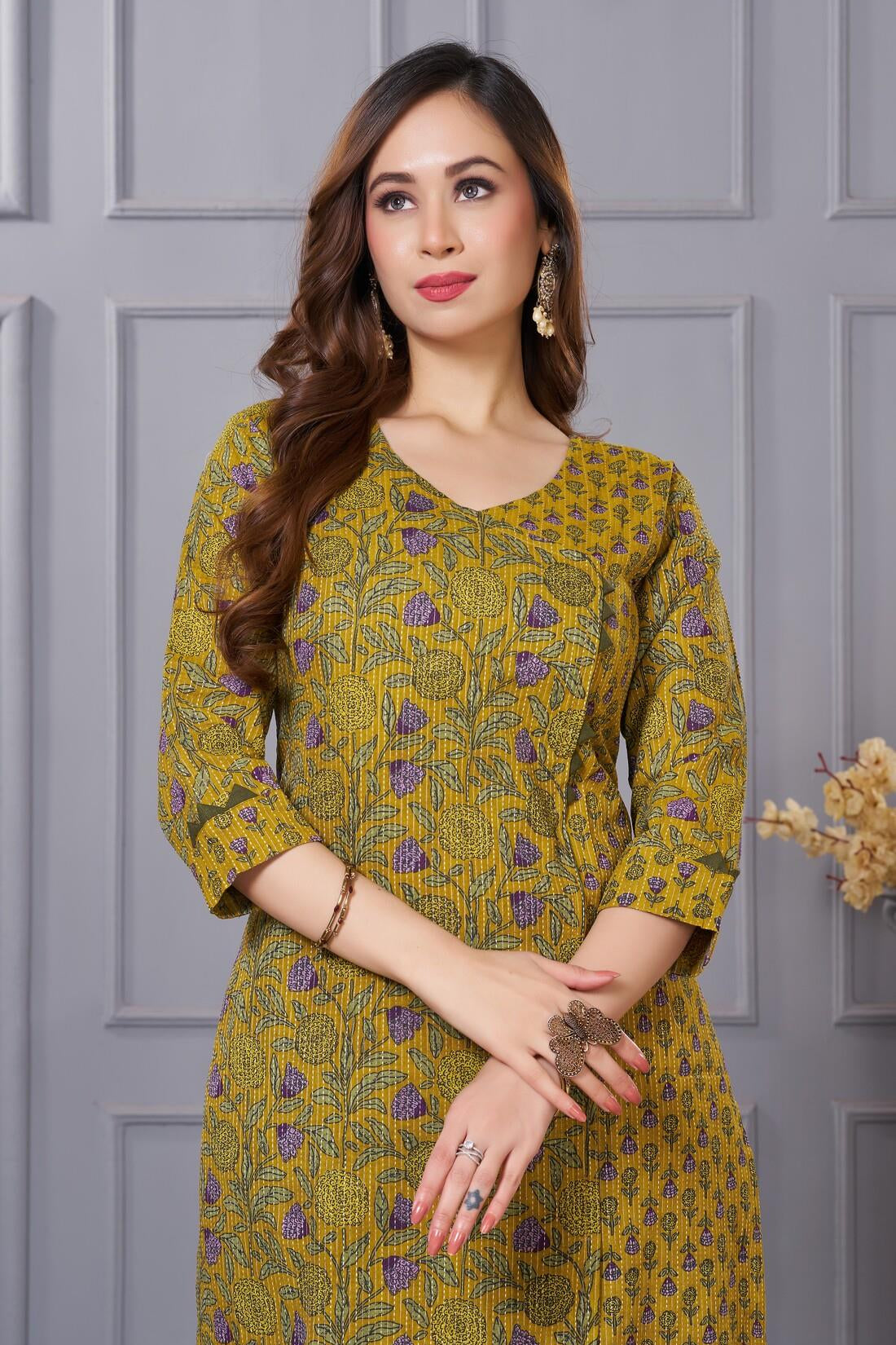 Close up view of the elegant neckline design showcasing white lace inserts and border trims on a mustard yellow cotton floral print kurta