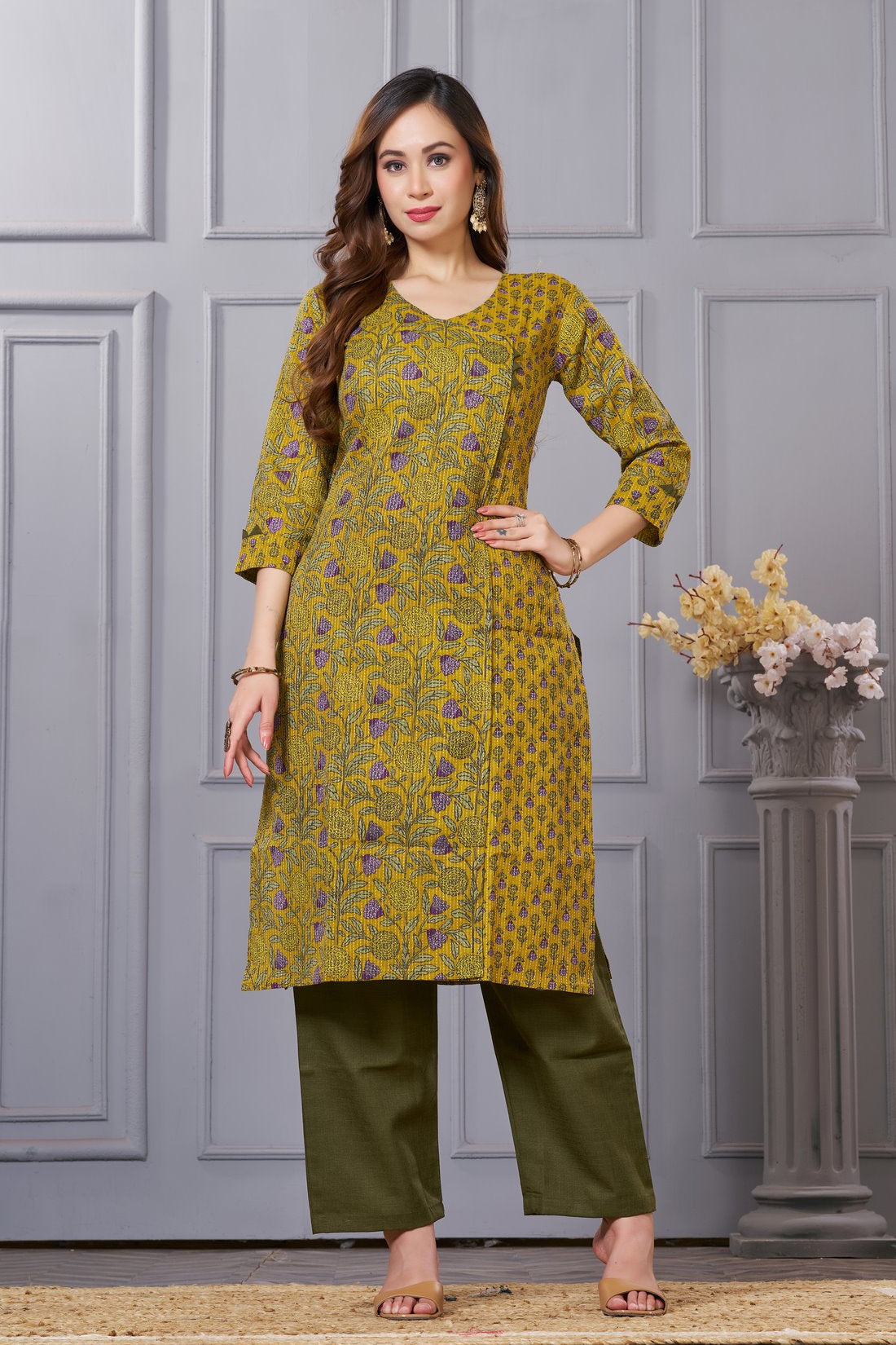 Front full length view of a model wearing a mustard yellow cotton floral print kurta set with matching pocketed straight pants