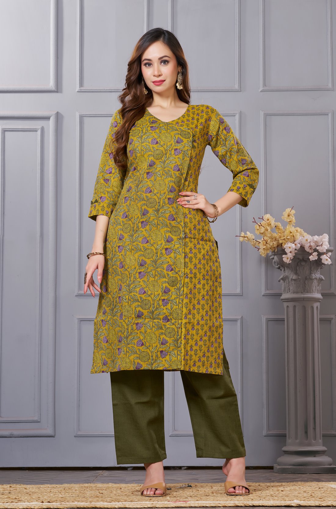 Front full length view of a model wearing a mustard yellow cotton floral print kurta set with matching pocketed straight pants