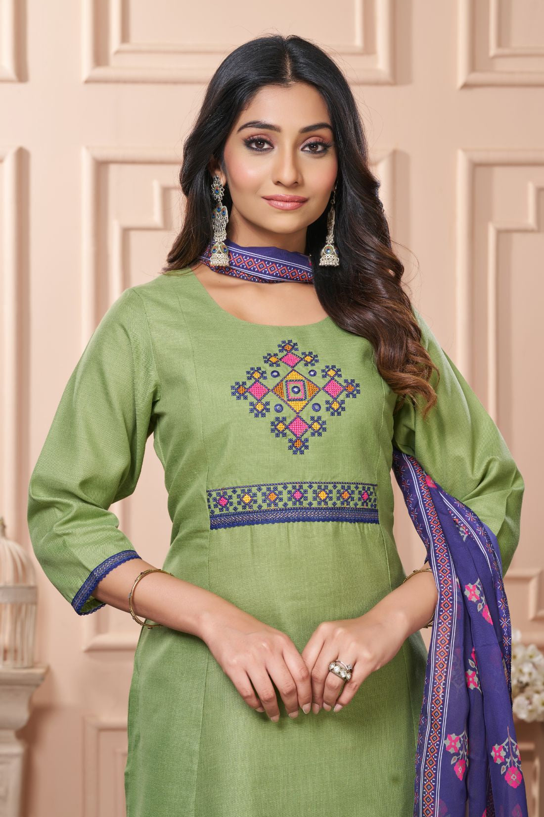 Detailed close up macro shot of the traditional cross stitch embroidery patterns surrounding the split crew neckline of a light green cotton kurta