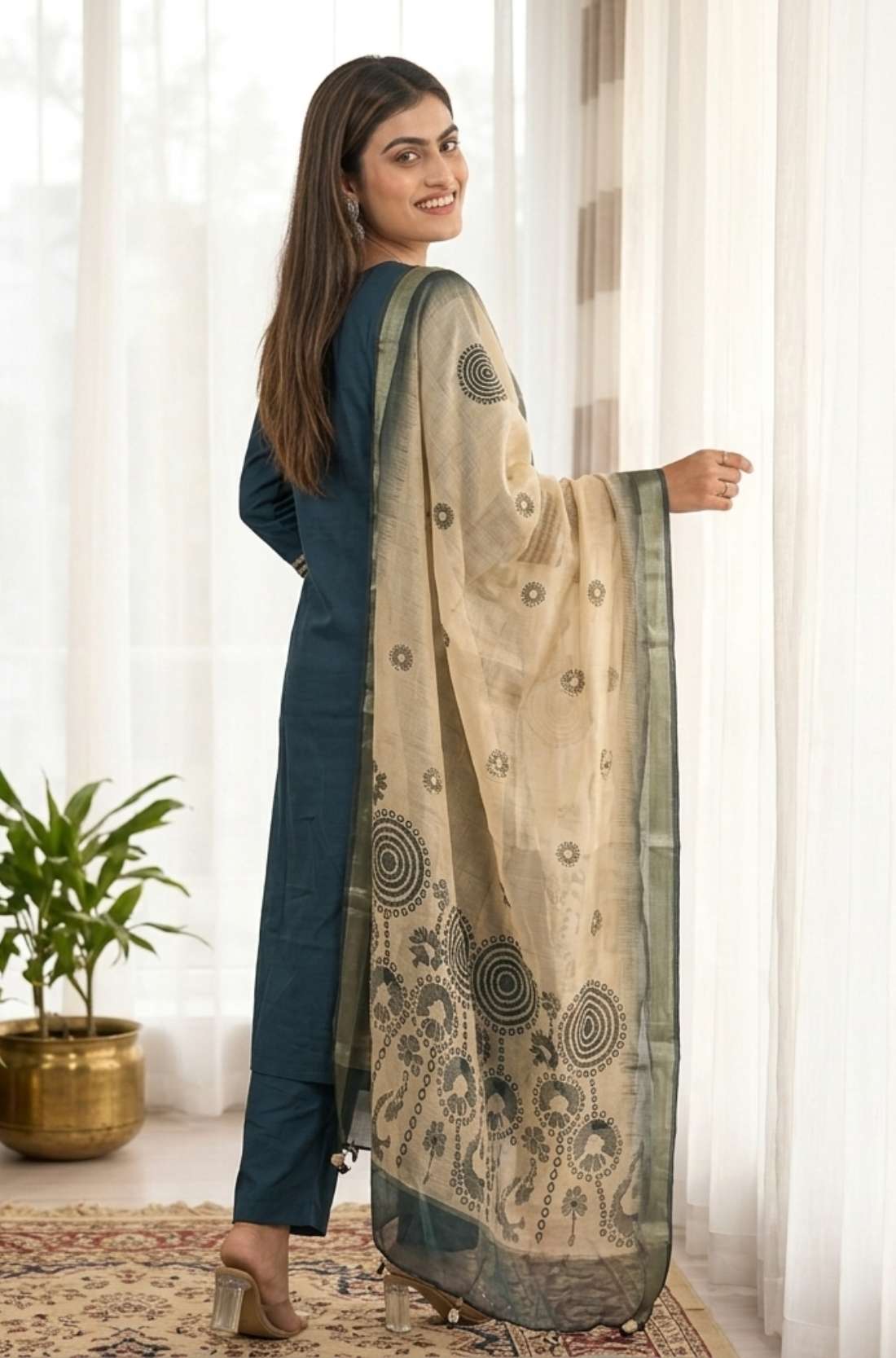 Side profile view of a model in a dark blue silk ethnic suit set with matching pants and a draped chanderi dupatta