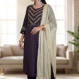 Side profile view of a woman wearing a dark purple crepe ethnic suit showcasing the clean fall of the straight pants and styled printed dupatta