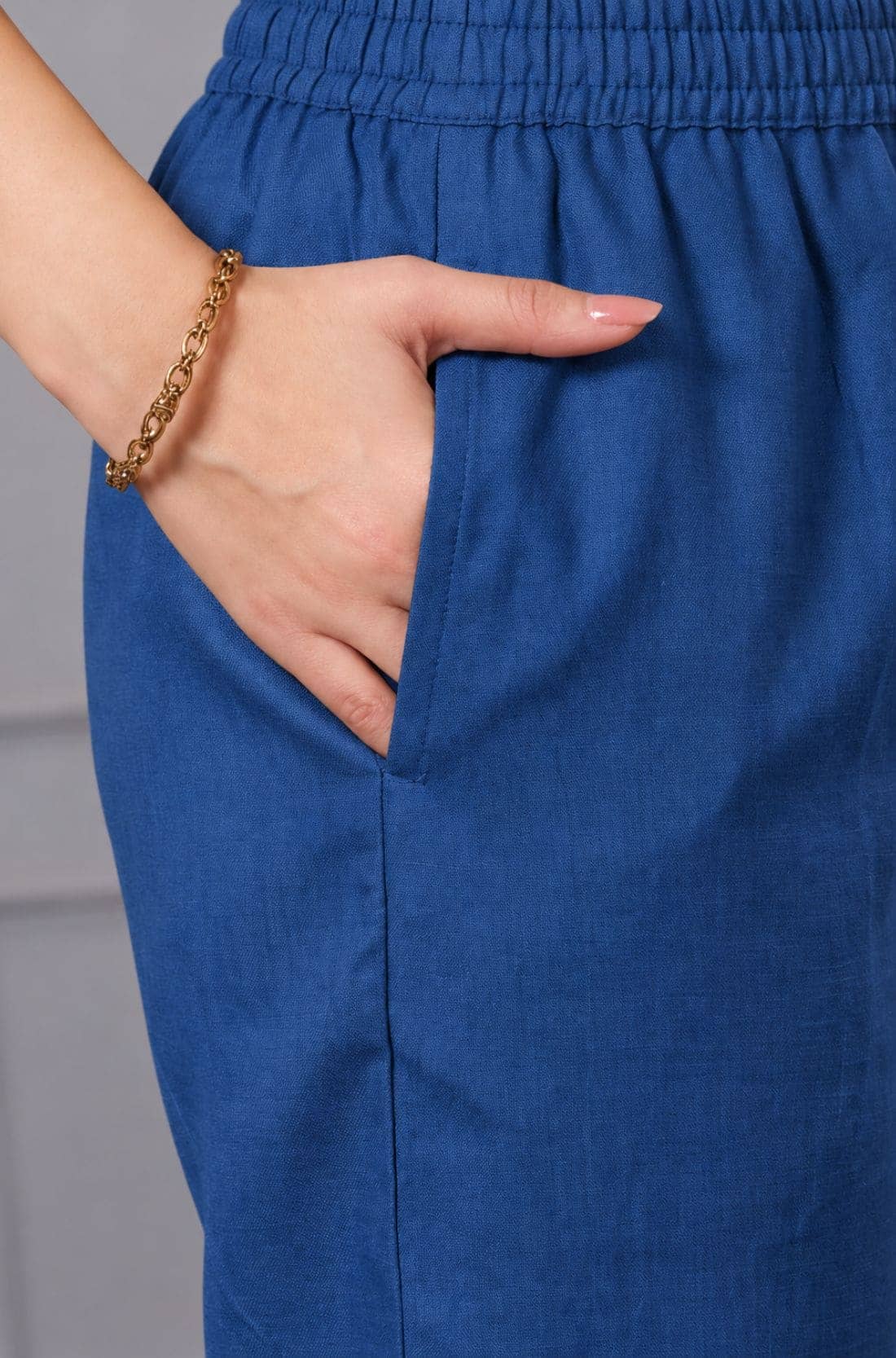 Close-up of blue cotton straight pants with elasticated waistband and side pocket, paired with a bright pink floral cotton kurta for women.