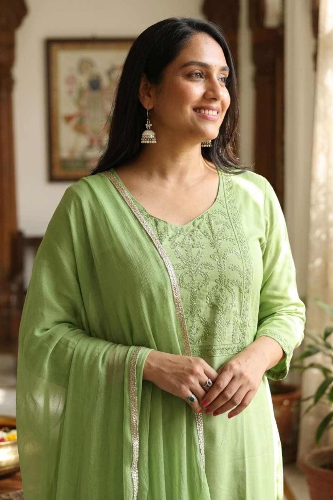 Close up shot of the delicate white thread embroidery, lace trims, and pintucks detailing on the neckline of a light green cotton kurta