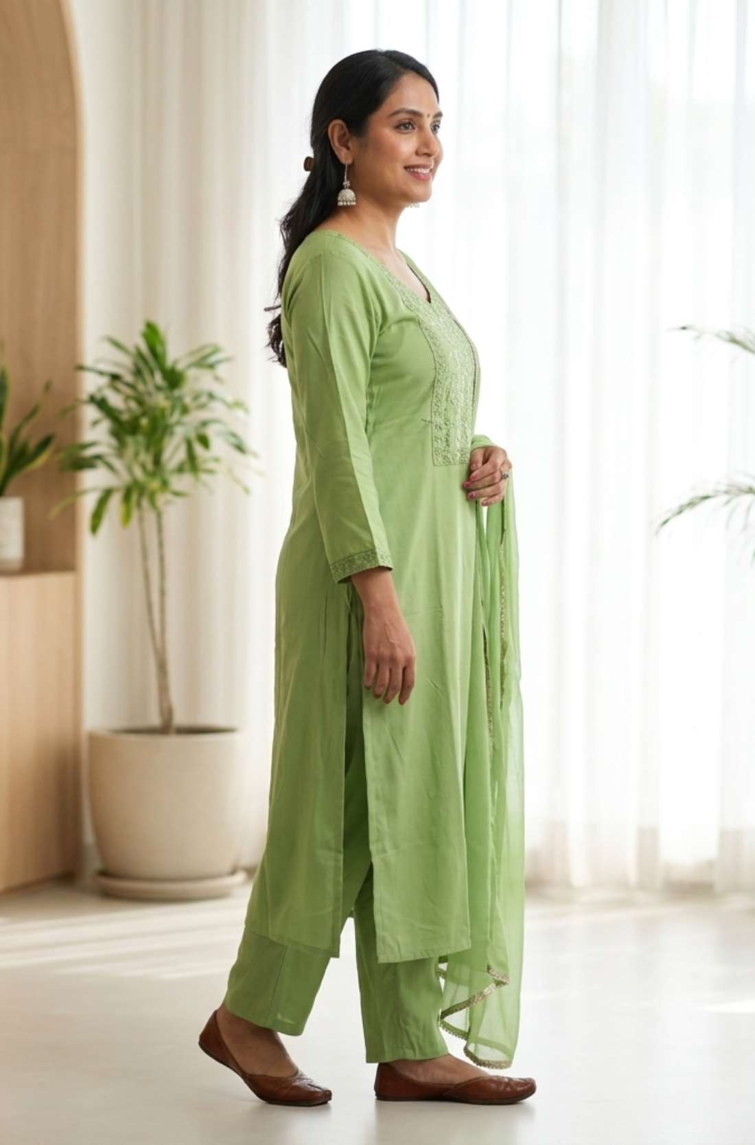 Side profile view of a model in a light green embroidered salwar suit showcasing the side slit and elegant dupatta drape