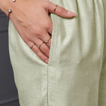 Close-up of the side pocket and elasticated waistband of light green pants from a women's kurta set.