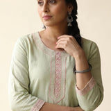 Close-up shot of a light green straight-fit kurta highlighting elegant pastel pink floral embroidery along the rounded keyhole neckline panel and matching embroidered lace borders on the three-quarter sleeves.
