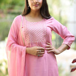 Close up shot of the delicate white thread embroidery, lace trims, and pintucks detailing on the neckline of a light pink cotton kurta