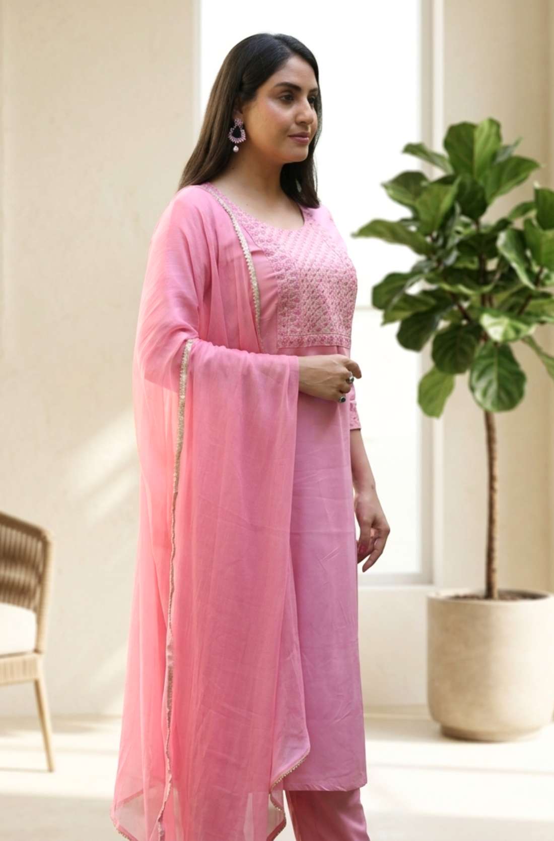 Side profile view of a model in a light pink embroidered salwar suit showcasing the side slit and elegant dupatta drape