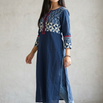 Full body side profile of a woman styling a long blue kurti with side slits and casual blue denim jeans.
