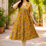 A woman posing gracefully in an mustard yellow pure cotton floral printed frock-style kurti dress, capturing the flowy movement of the flared hemline.