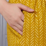 Close up view of the functional side utility pocket stitched seamlessly into a floral cotton straight kurta, showing a hand resting inside the pocket over contrasting purple chevron print trousers.