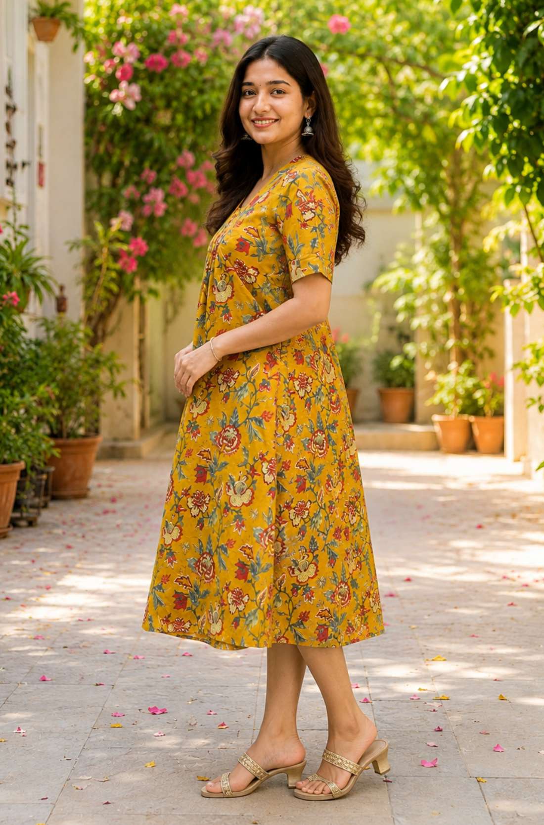 Side profile view of a woman wearing an ochre yellow cotton floral print frock-style kurti dress, showcasing the relaxed-fit elbow sleeves and A-line drape.