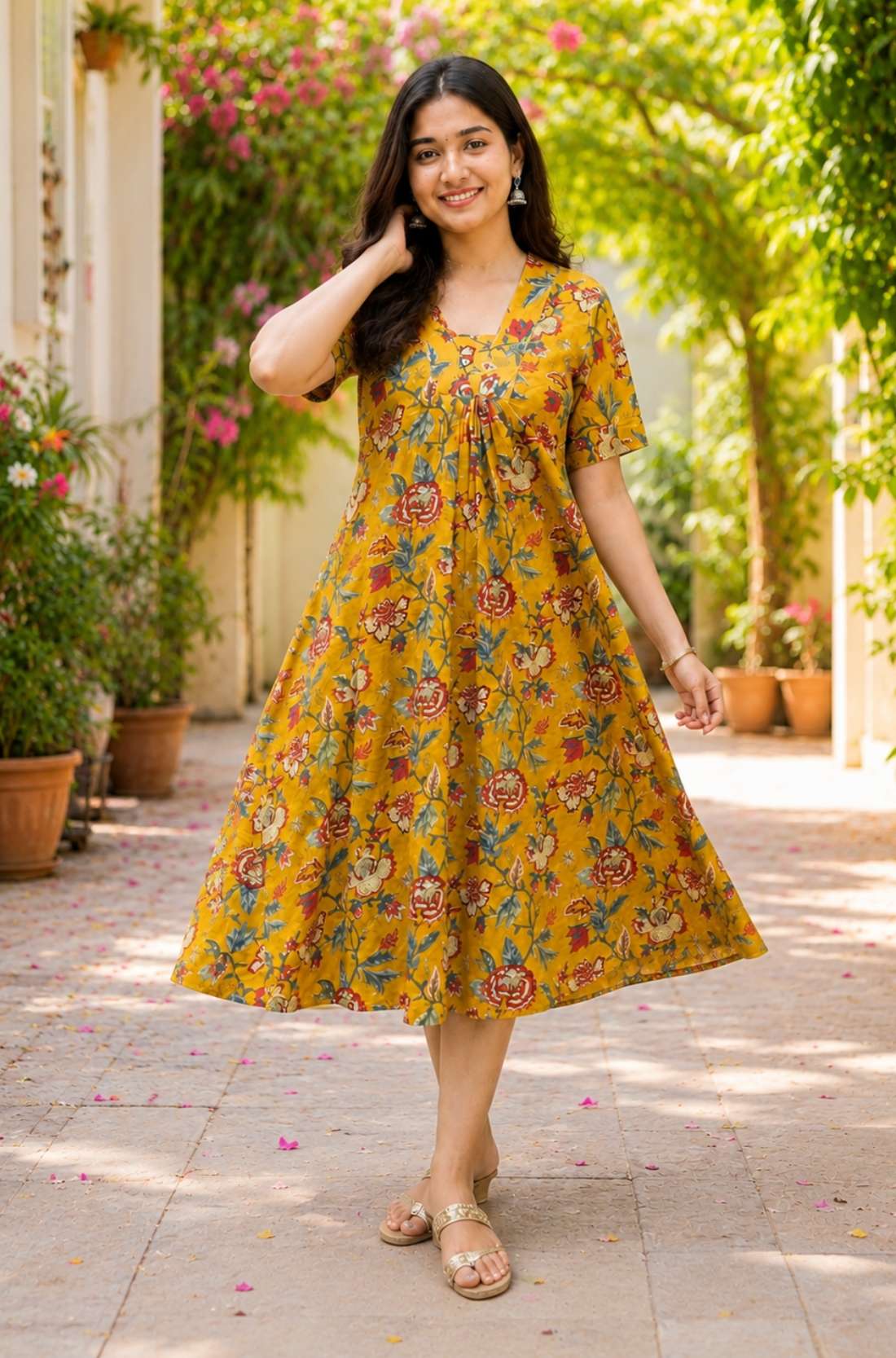 A woman posing gracefully in an ochre yellow pure cotton floral printed frock-style kurti dress, capturing the flowy movement of the flared hemline.