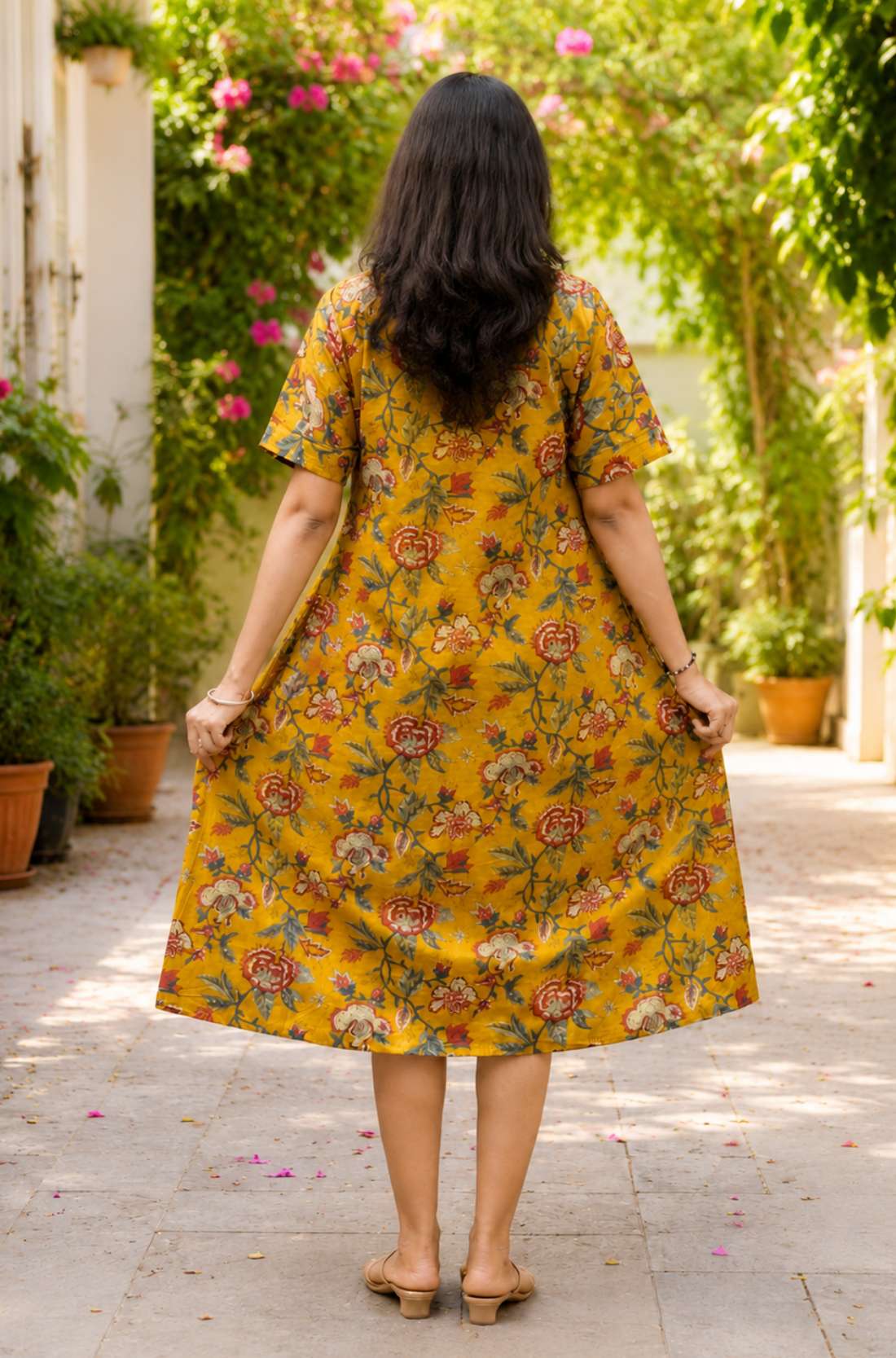 Full back view of the ochre yellow printed cotton frock kurti dress, emphasizing its flowy silhouette and continuous vibrant floral print pattern.