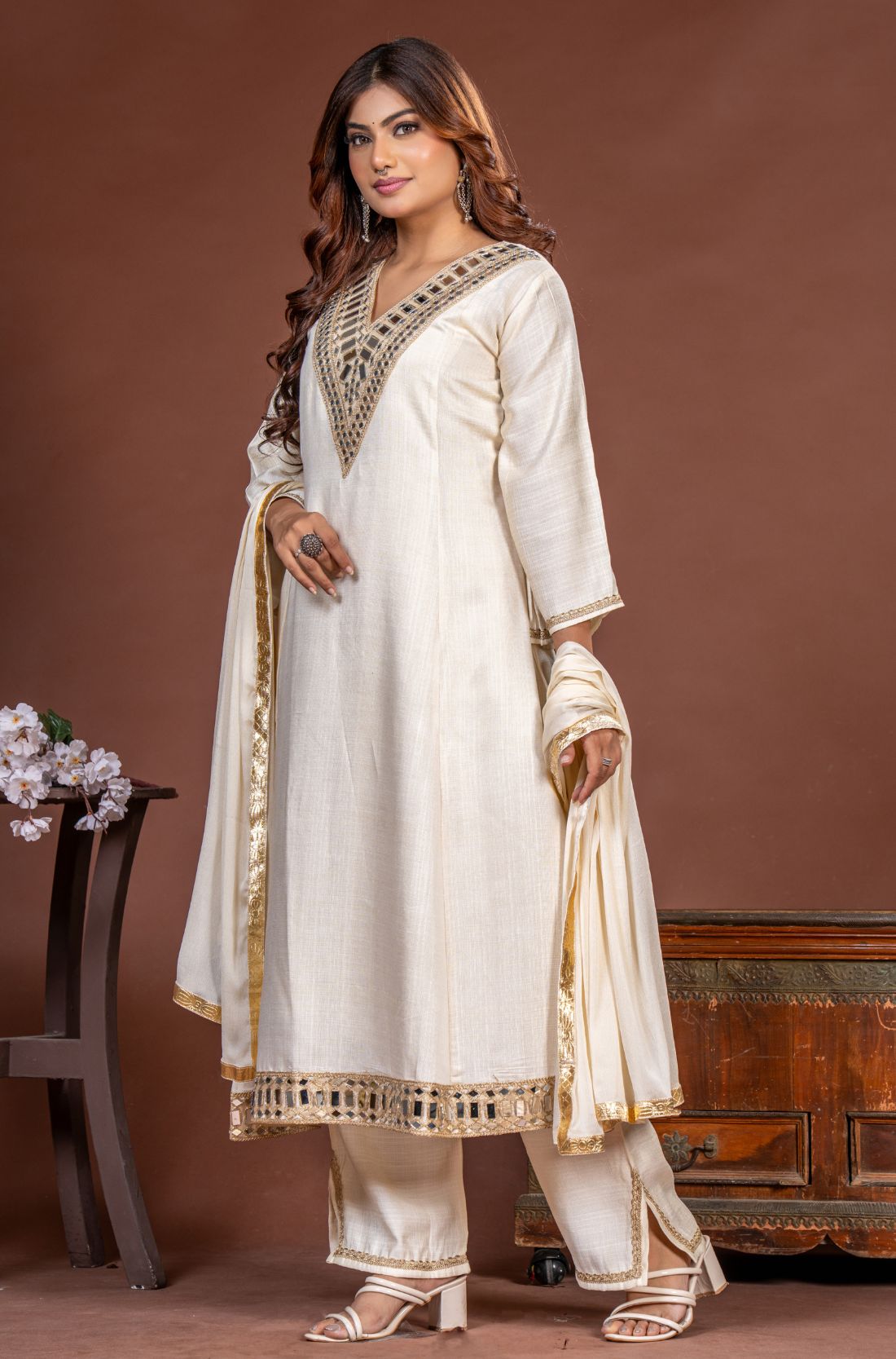 Off white Vatican Silk A-line kurta set for women, angled front view with mirror work, straight pants and chiffon dupatta