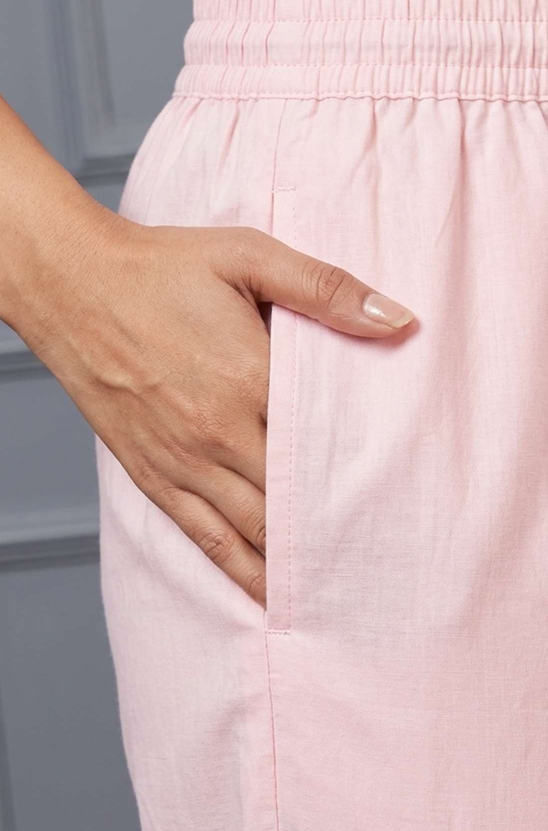 Close up view highlighting the convenient functional side utility pocket tailored into the straight pants of a pink pure cotton pintucks kurta set, showing a hand resting inside the pocket.