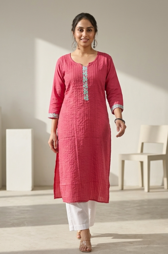A full-length view of a woman walking gracefully while wearing a pink textured kurta and white palazzo pants.