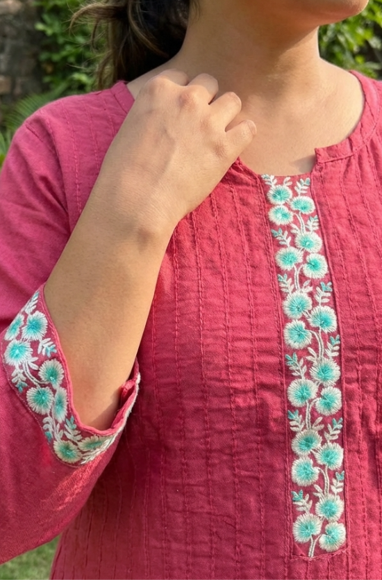 A close-up shot of the pink kurta neckline and sleeves, featuring intricate floral thread embroidery.
