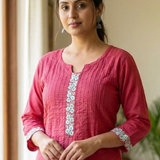 A portrait of a woman wearing a pink embroidered kurta, showcasing the elegant fit and fabric texture.