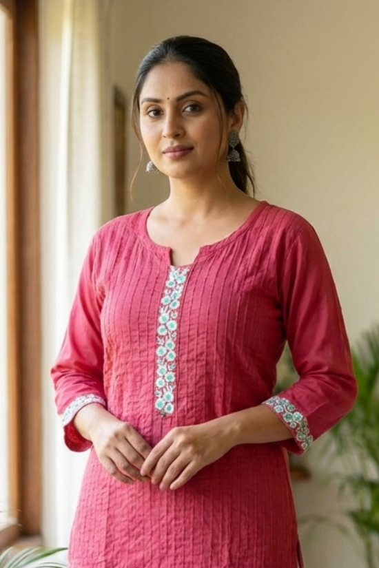 A portrait of a woman wearing a pink embroidered kurta, showcasing the elegant fit and fabric texture.