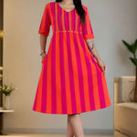 Model wearing a pure handloom cotton pintucks tunic dress in pink piano featuring vibrant pink and orange vertical stripes, a flare silhouette, and elbow-length cuffed sleeves.