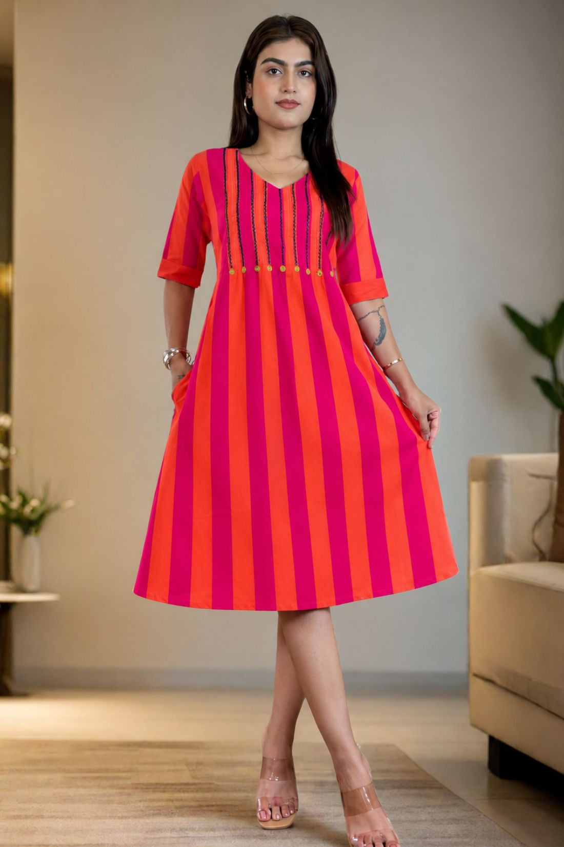 Model wearing a pure handloom cotton pintucks tunic dress in pink piano featuring vibrant pink and orange vertical stripes, a flare silhouette, and elbow-length cuffed sleeves.