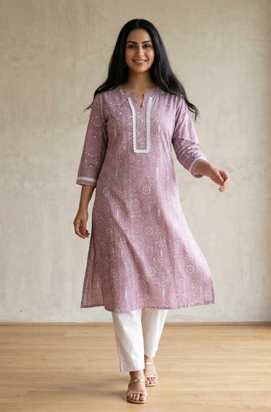 A woman standing in a purple printed ethnic kurta paired with white trousers, displaying a casual yet stylish look.